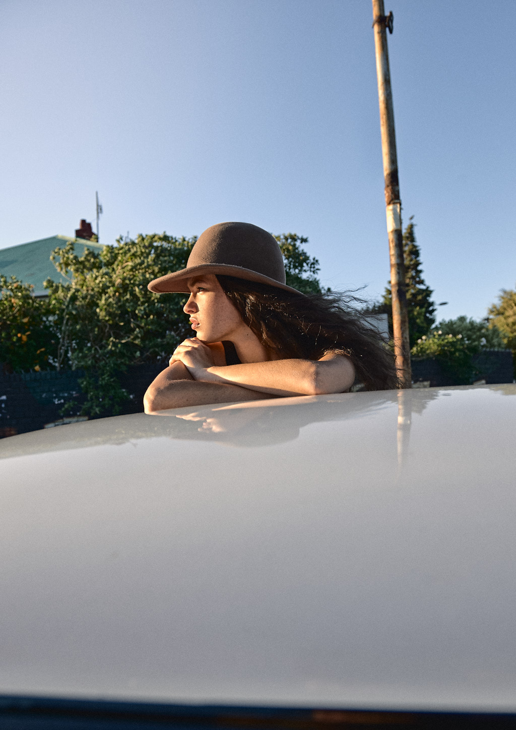 Woman wearing a Brixton hat and leaning on a classic Mini car.