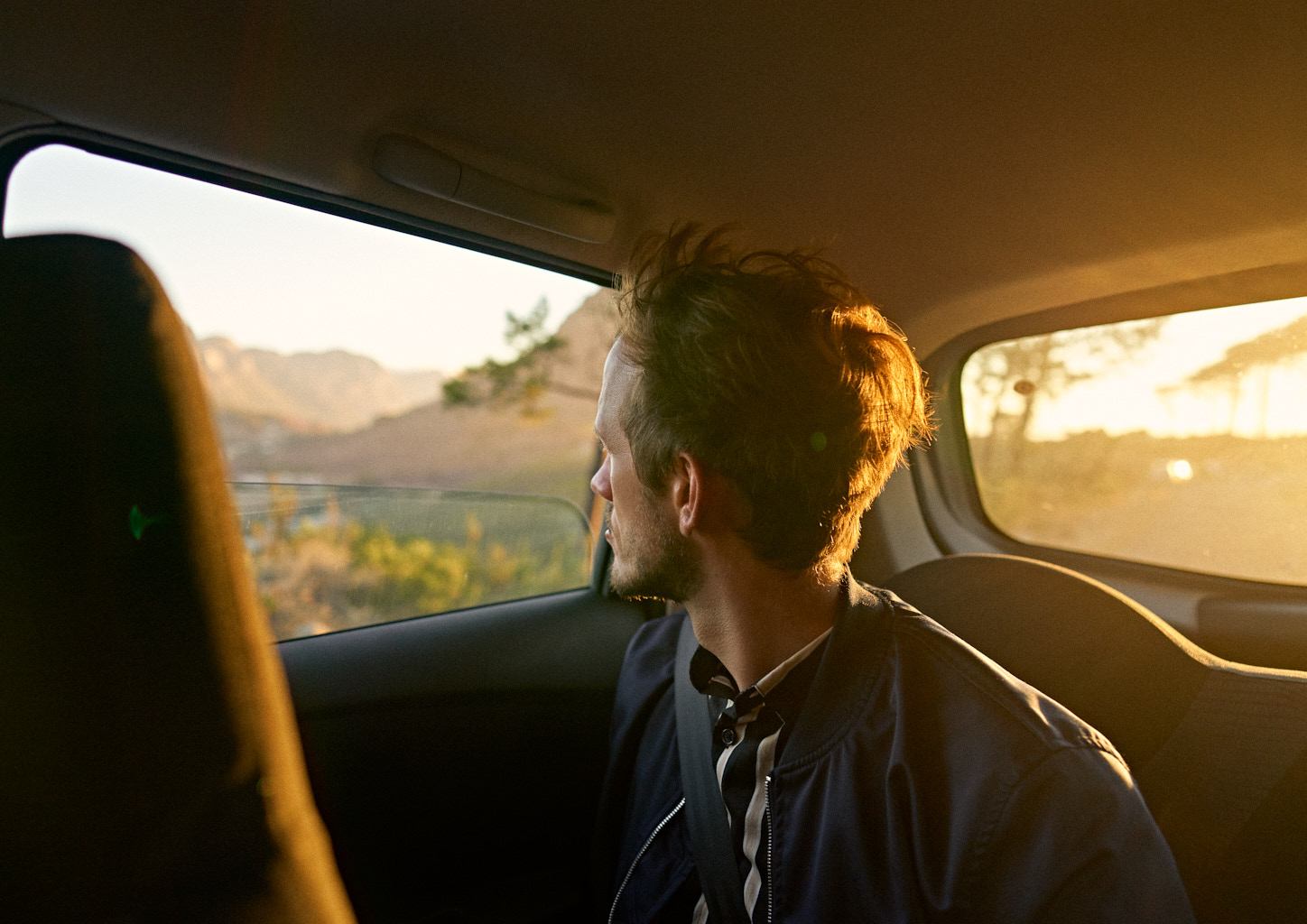 Man, 30 years old, looking out of the car window into the distance.
